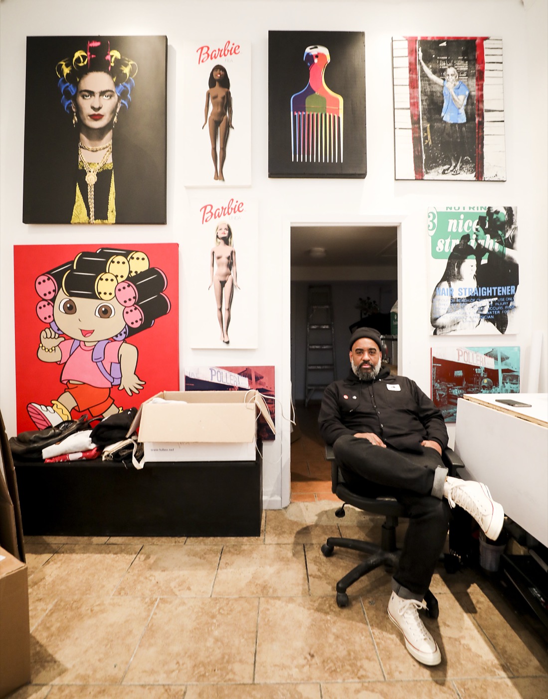 Artist seated beneath a wall of pop-art canvases