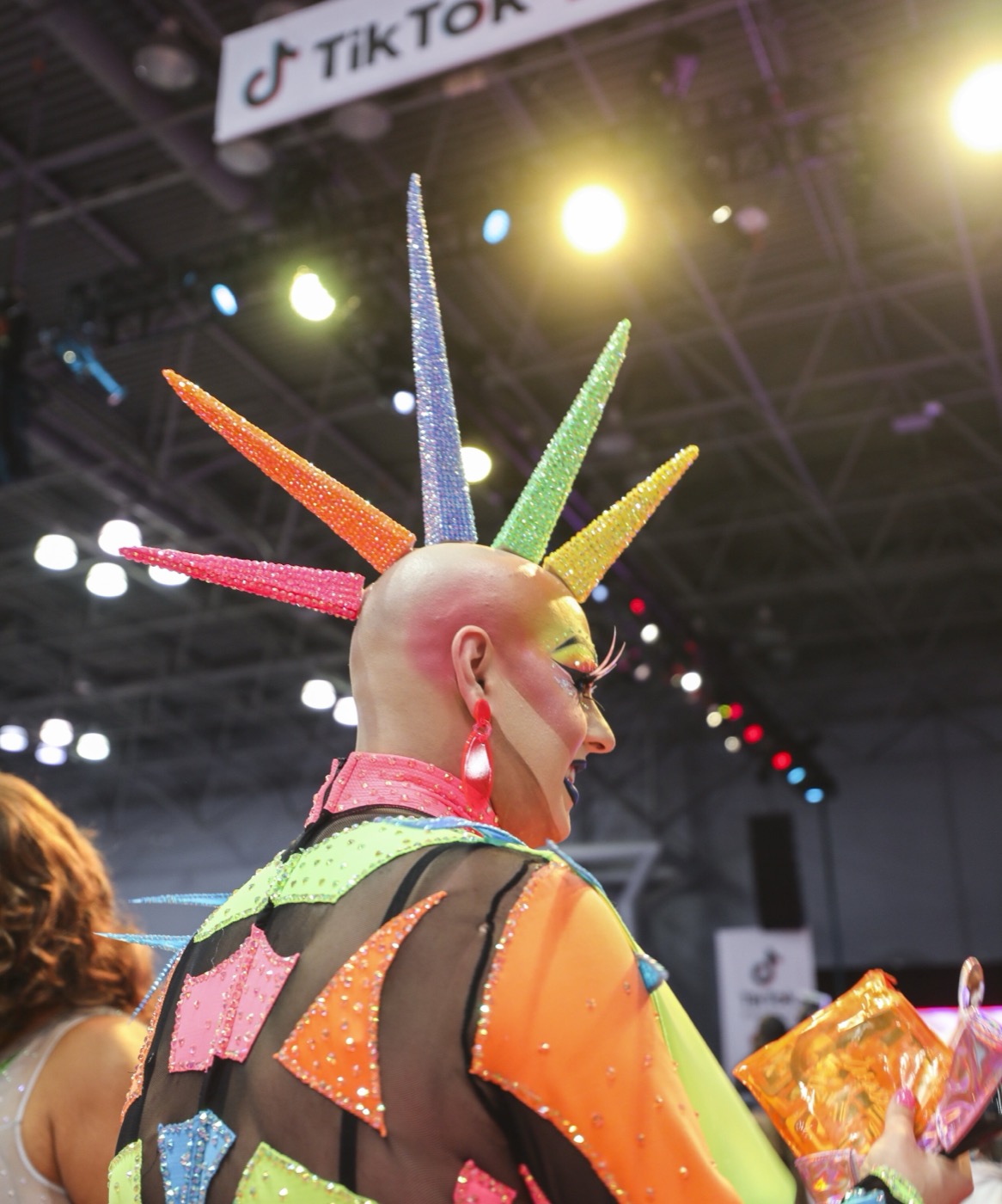 Performer with rhinestone spike crown backlit by stage lights