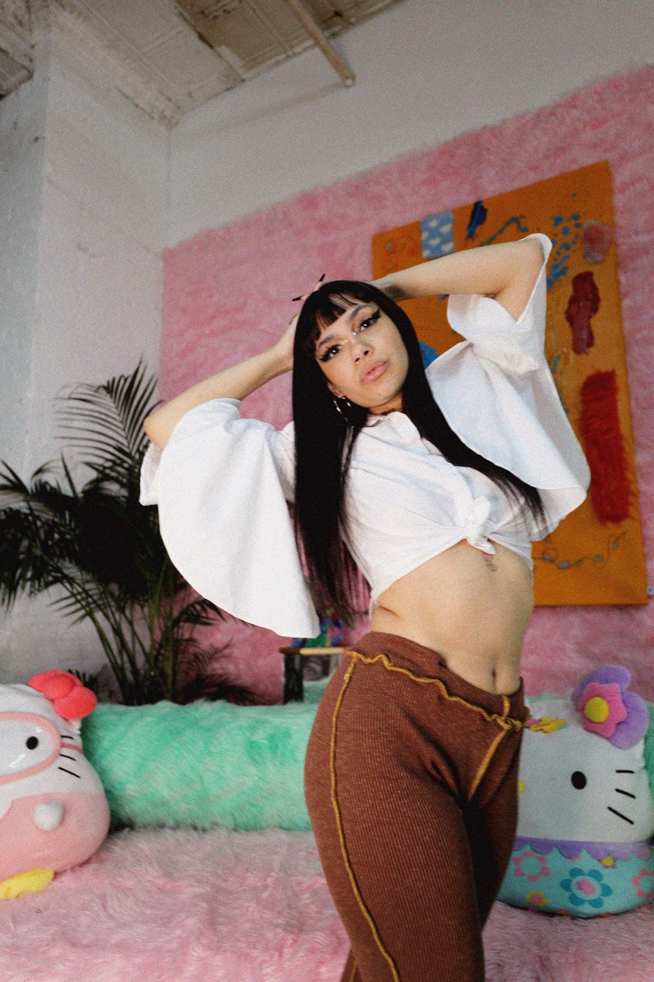 Model posing arms-up against a pink fur backdrop