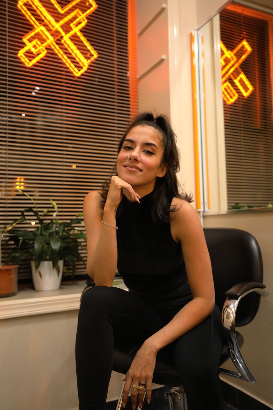 Woman seated in a salon chair beneath neon signs