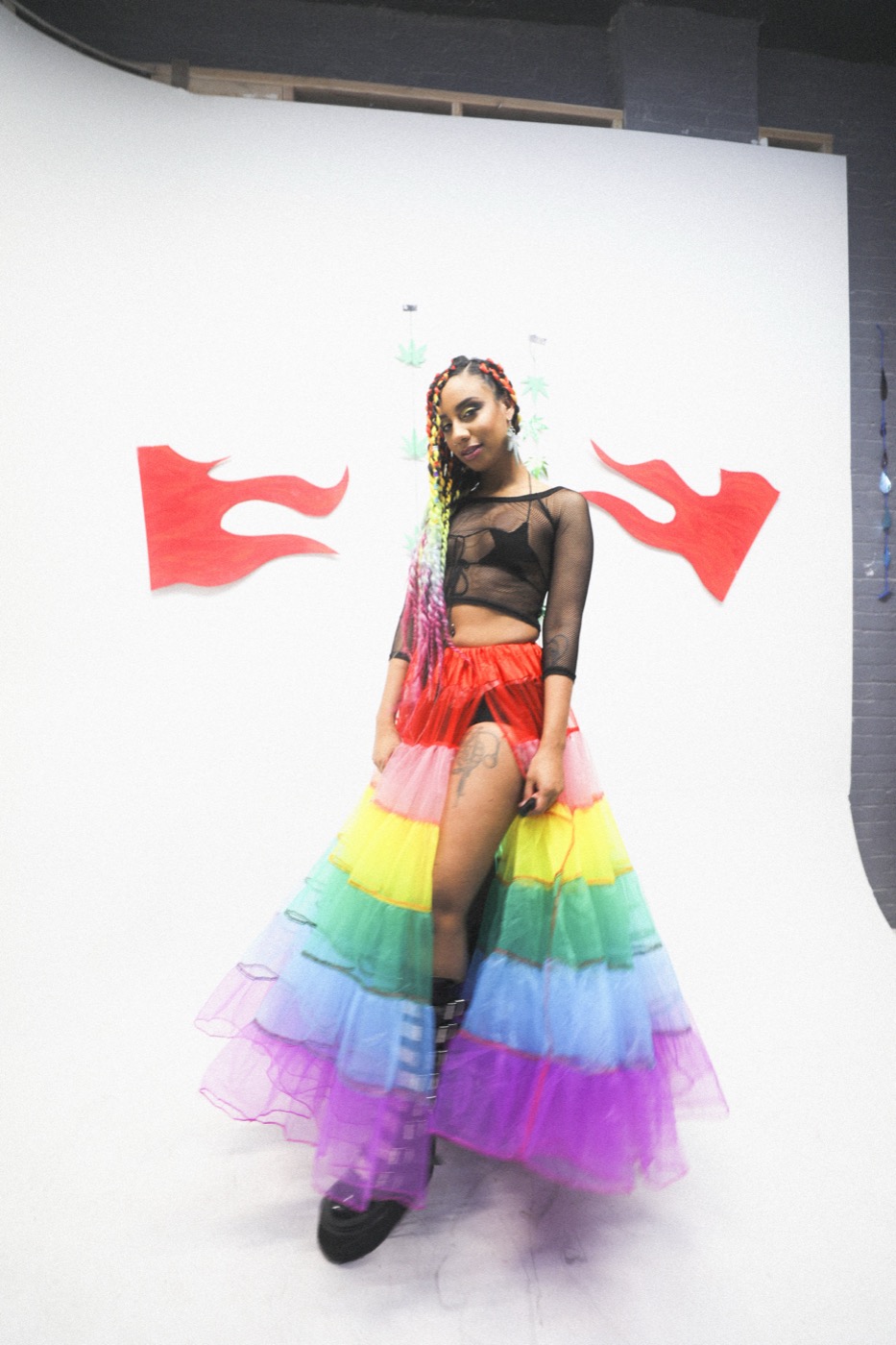 Model in tiered tulle skirt on white seamless with paper flames